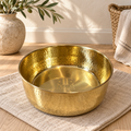 AURORA hand-hammered brass pet food bowl on a woven mat beside an olive branch and towel basket
