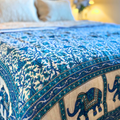 Handcrafted cotton quilt with Jaipuri floral design and blue elephant border.