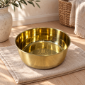 Gray cat eating wet food from the DUNE smooth-finish brass pet food bowl on a wood floor