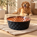 Golden Retriever lying down beside the ONYX black diamond-hammered copper pet bowl on a woven mat